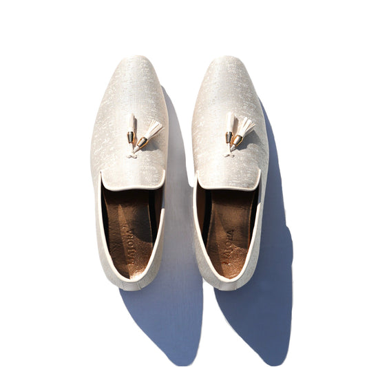 White fabric men's Mojaris/Mojris with tassels, featuring gold insoles and embossed Majora logo. Ideal Indian wedding shoes.